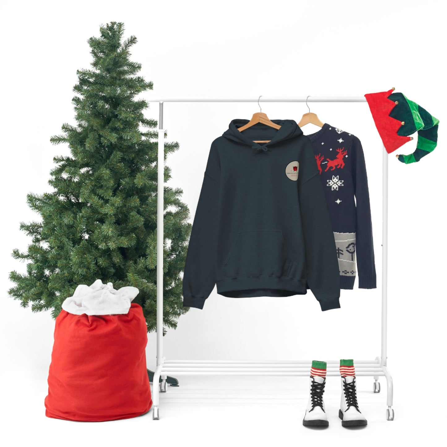 Black Godzilla's Fury Hoodie displayed on a hanger alongside festive holiday apparel and accessories, set next to a decorated Christmas tree and red sack.