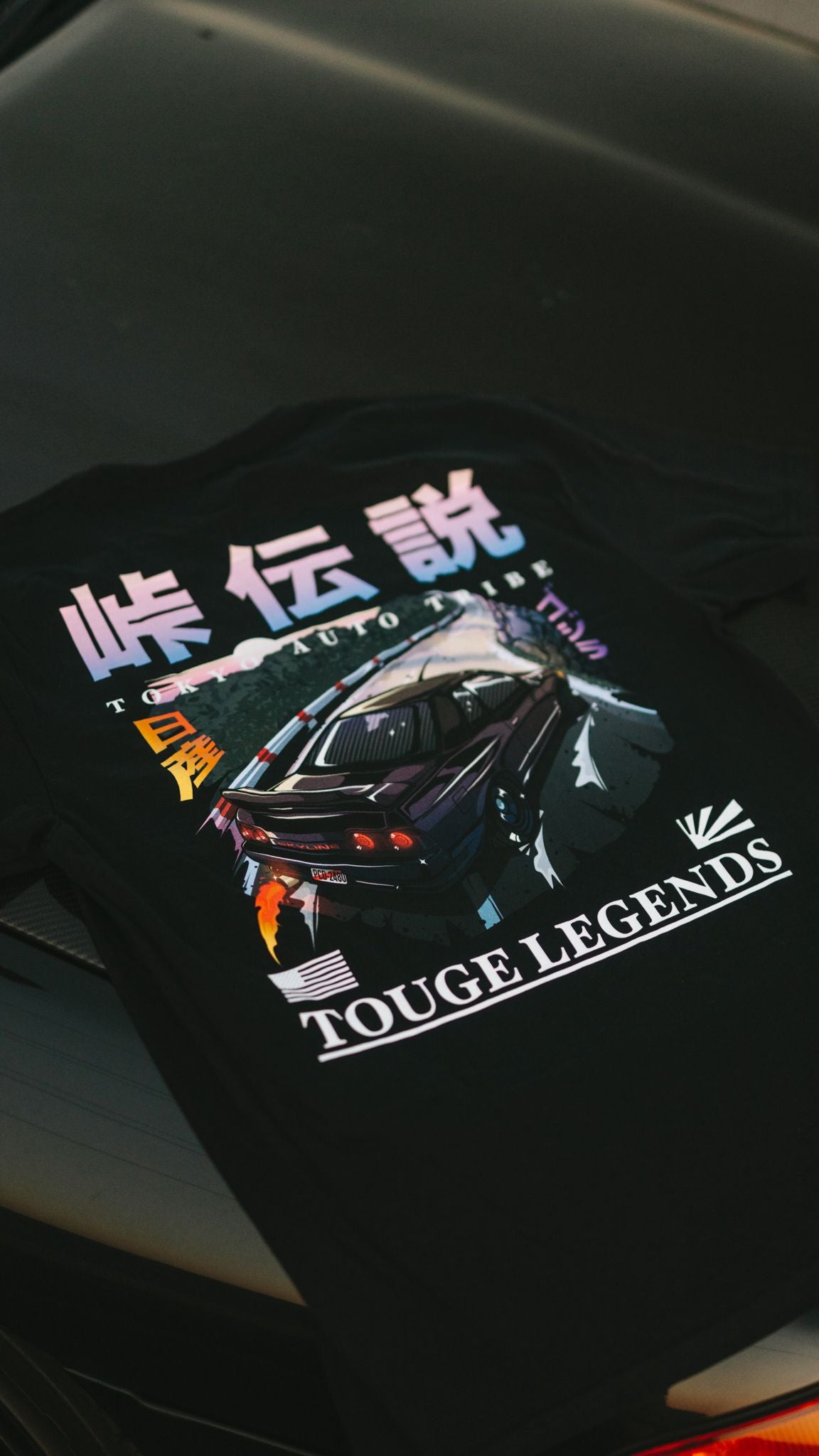 Black graphic tee featuring colorful artwork of a drifting Nissan Skyline on touge roads with Japanese text and "Touge Legends (more colors)" branding.