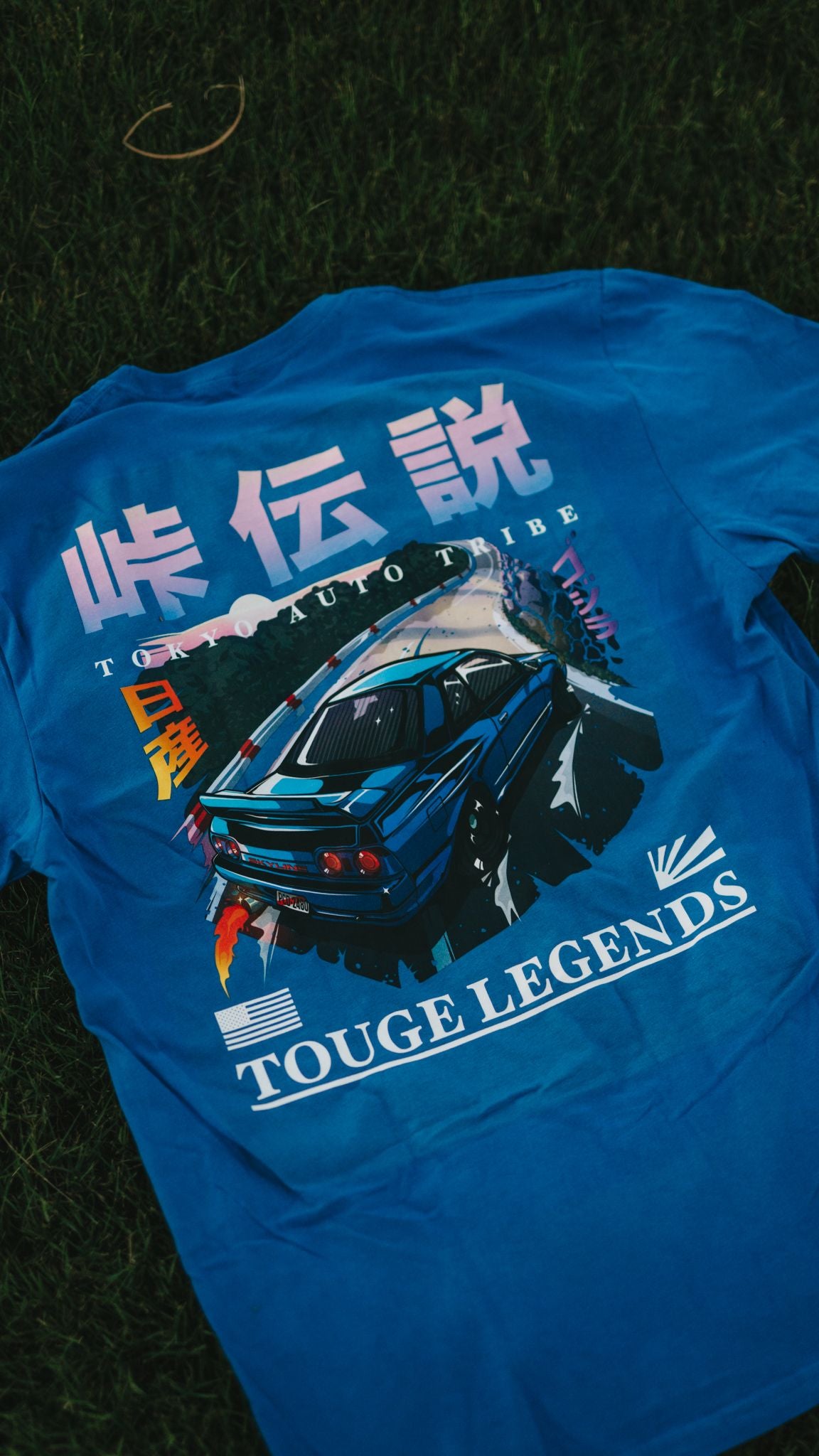 Blue graphic tee featuring a dynamic illustration of a drift car on a mountain road, with bold Japanese characters and the text "Touge Legends (more colors)" designed for fans of Japanese car culture and late-night drives.