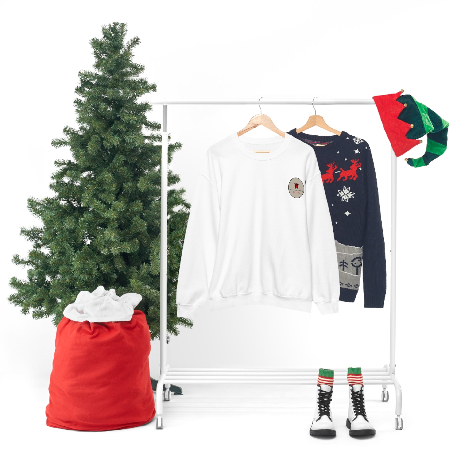 Wagon Chibi Sweater hanging on a rack next to a festive navy sweater with reindeer and snowflake patterns, accompanied by Christmas decor including a decorated tree and holiday-themed accessories.