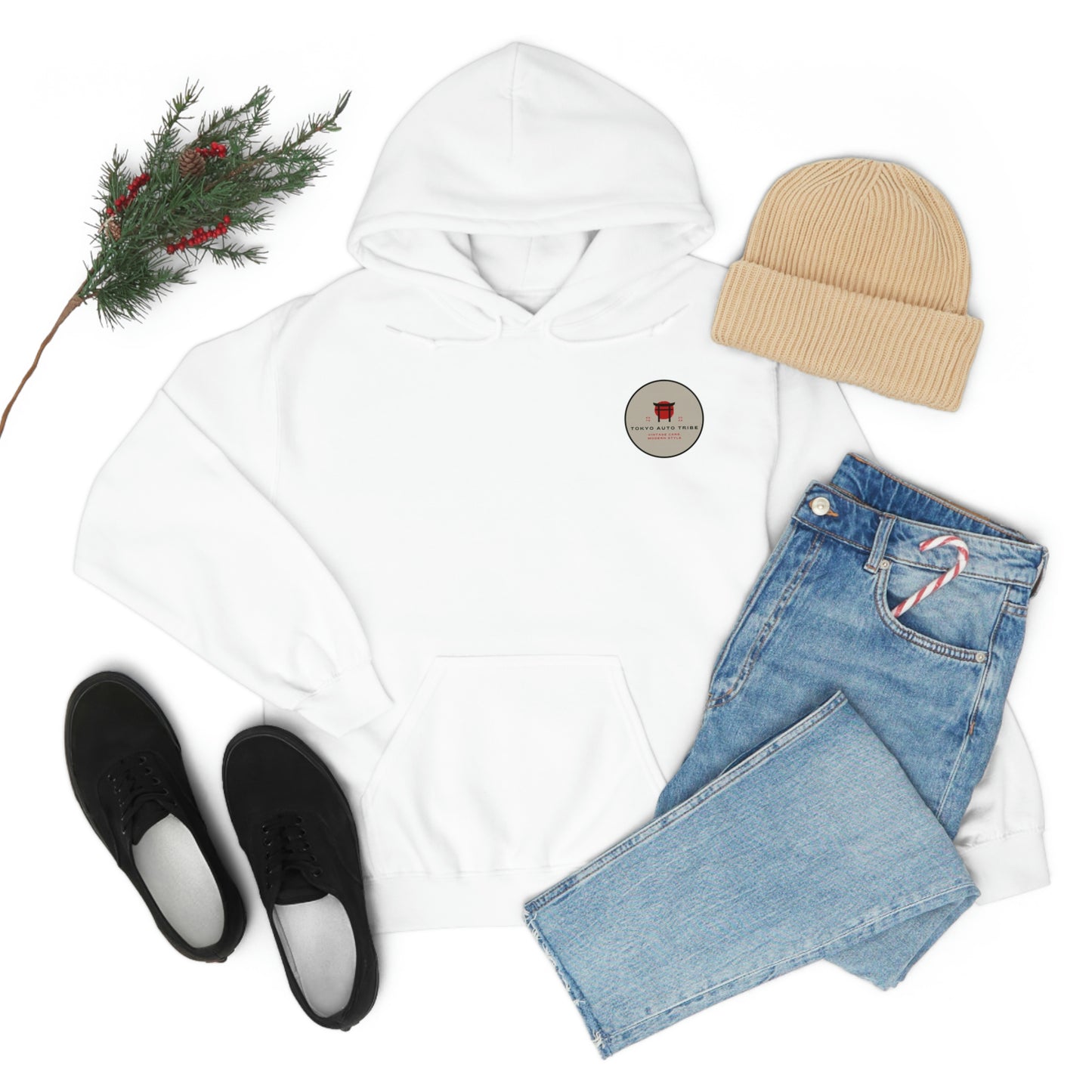 White Groovy Grocery Runner Hoodie with small logo on chest, paired with light blue jeans holding a candy cane, beige beanie, black sneakers, and a sprig of pine with red berries.