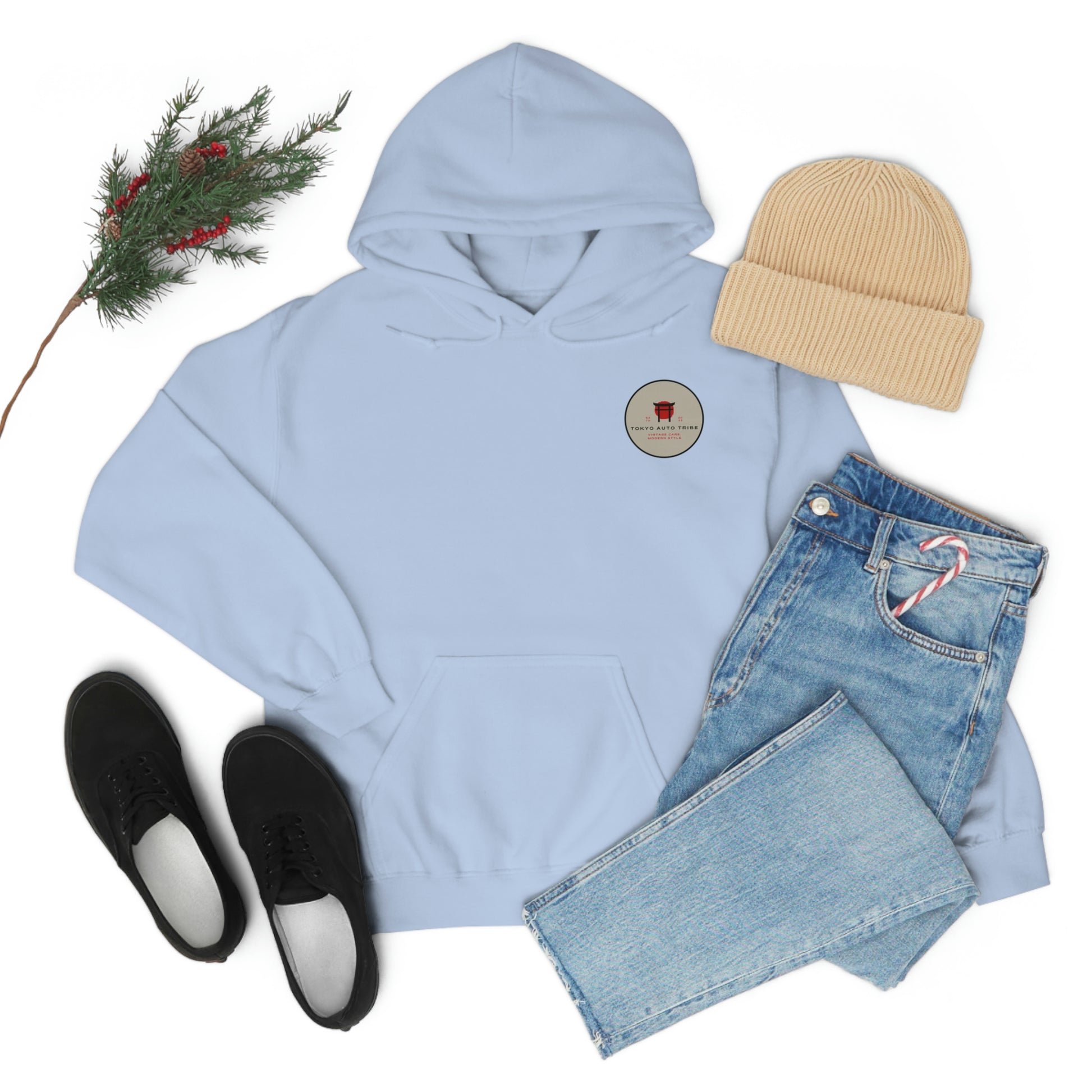 Light blue Groovy Grocery Runner Hoodie with a small circular logo on chest, paired with light wash jeans, black sneakers, and a tan knit beanie, styled with a sprig of greenery.