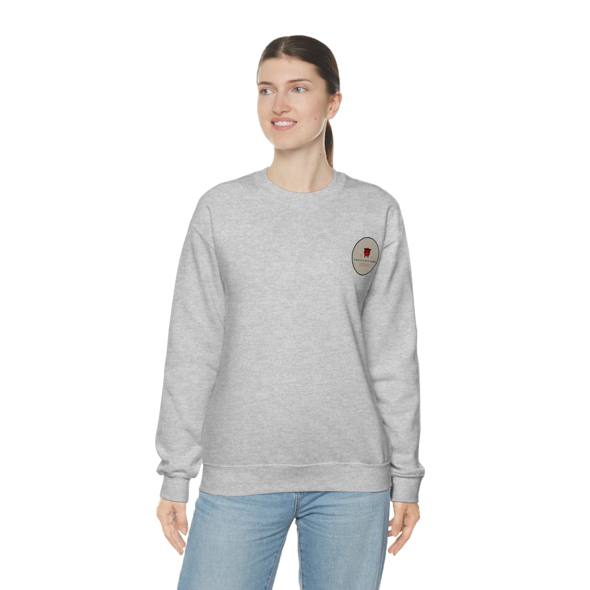 Woman wearing a gray Wagon Chibi Sweater with a small red and black graphic on the upper chest, styled casually with light blue jeans, embodying Japanese car culture inspired streetwear.