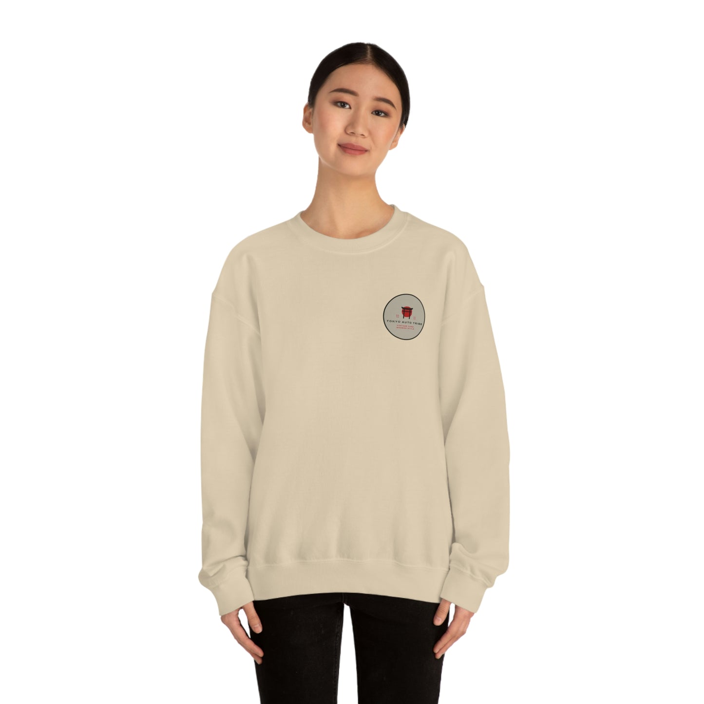 Woman wearing a beige crewneck sweatshirt featuring a small circular graphic on the chest, styled as The Family Wagon Sweater, inspired by Japanese car culture and late-night drives.