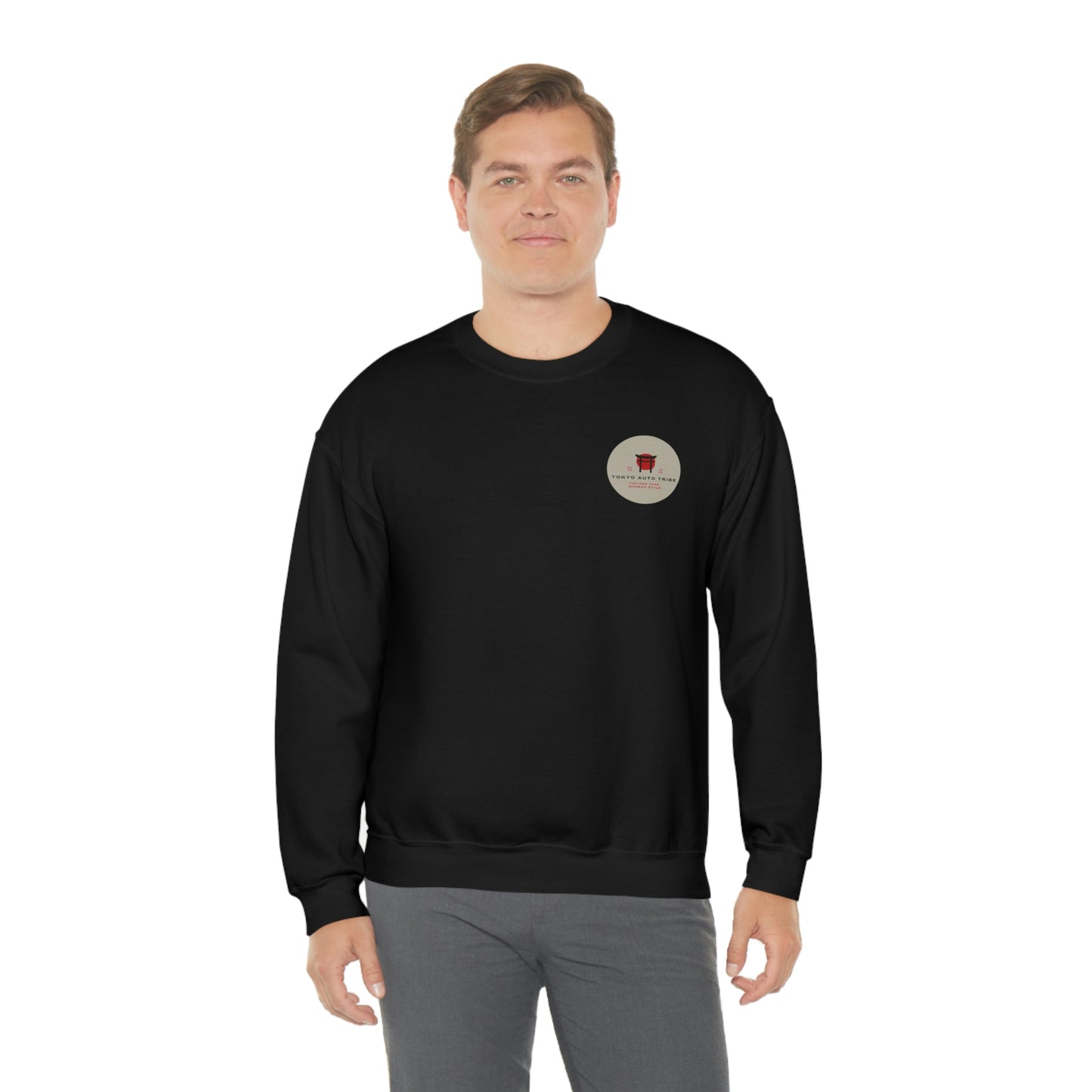 A man wearing The Family Wagon Sweater in black featuring a small circular vintage car culture graphic on the chest, blending JDM streetwear with automotive nostalgia.