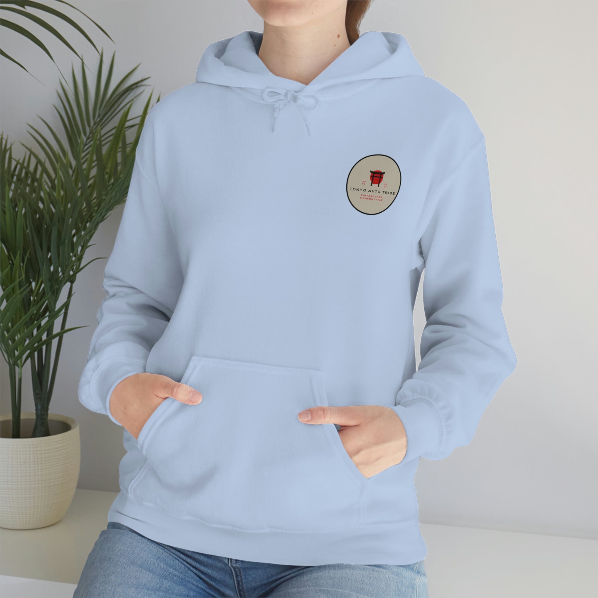 Person wearing a light blue Groovy Grocery Runner Hoodie with a small circular Tokyo Auto Tribe logo on the chest, styled for fans of Japanese car culture and late-night drives.