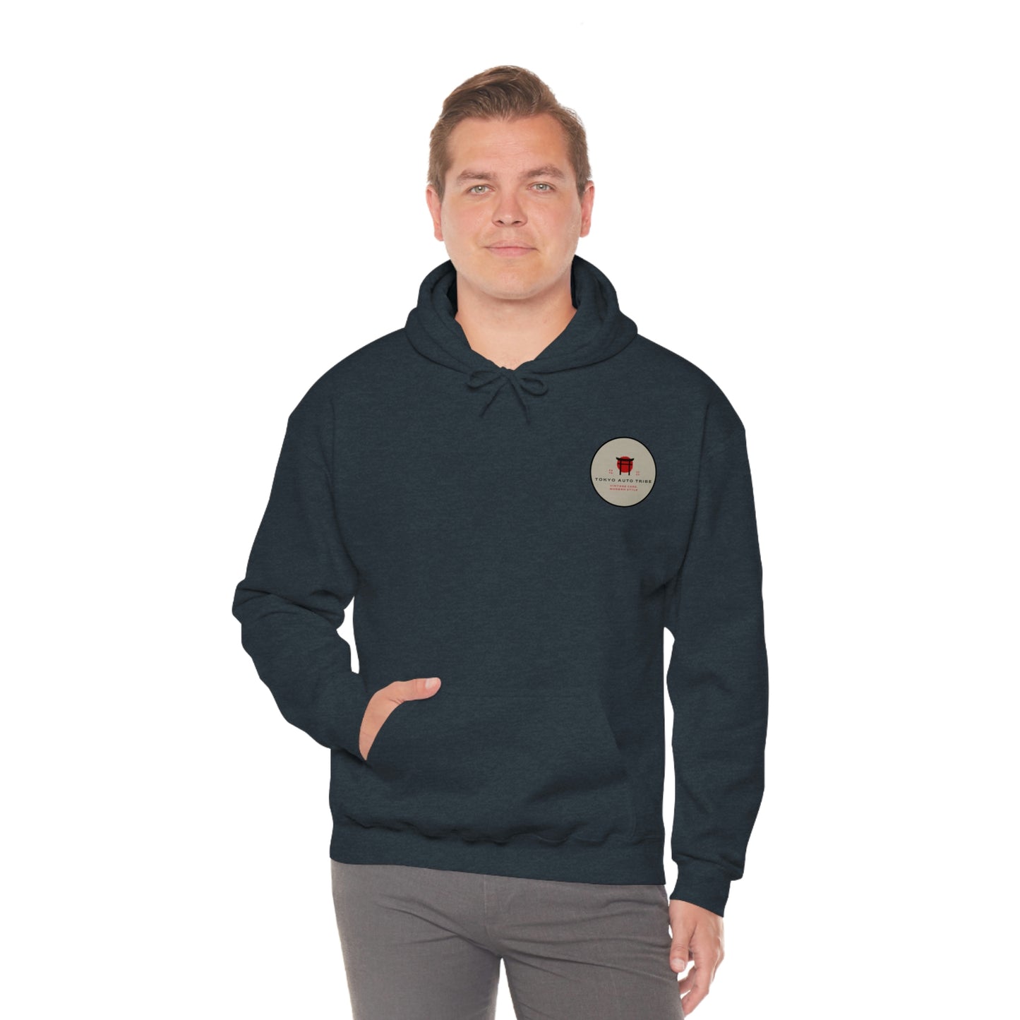 Man wearing a dark hoodie with a small circular logo on the chest featuring a red graphic and text, styled as the Groovy Grocery Runner Hoodie inspired by Japanese car culture and late-night drives.