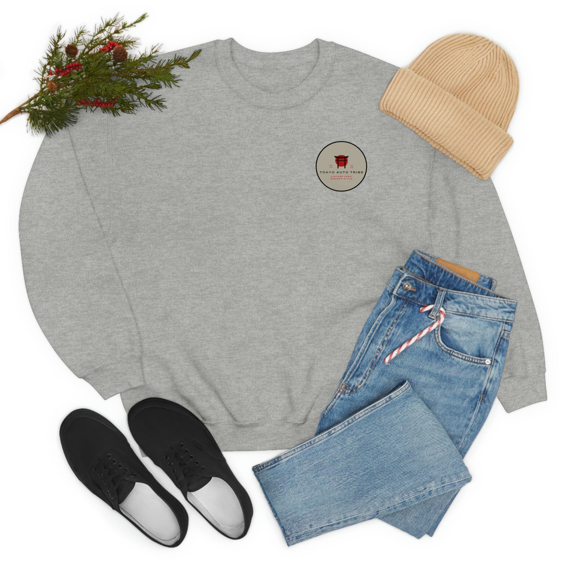 The Family Wagon Sweater in light gray featuring a small red graphic on chest, styled with blue jeans, black sneakers, beige knit hat, and festive greenery, capturing JDM streetwear vibes.