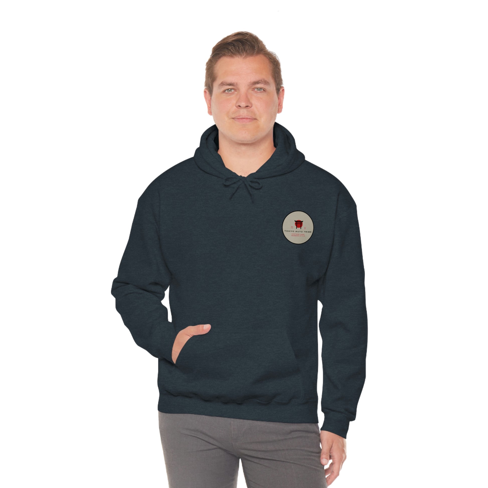 Man wearing a dark hoodie with a small circular graphic on the chest, posing with one hand in the pocket of the Godzilla's Fury Hoodie, styled for casual streetwear.