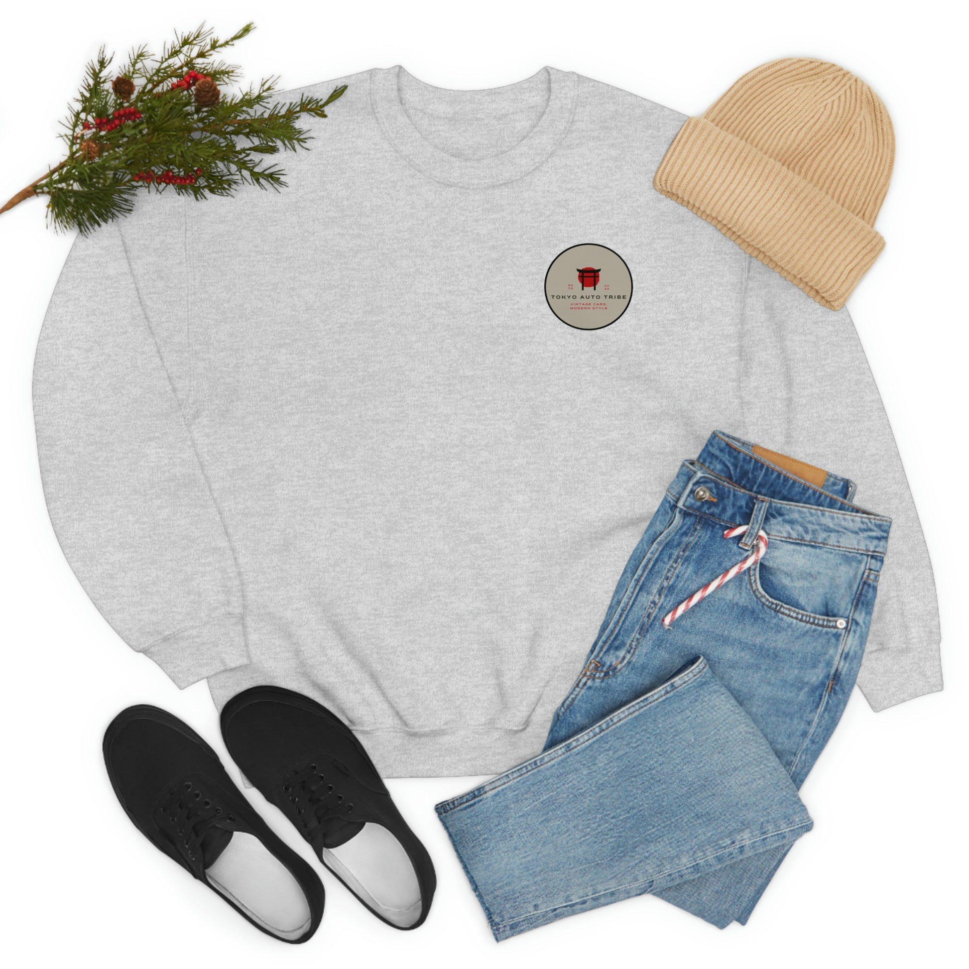 The Family Wagon Sweater in light gray laid flat with a beige knit hat, blue jeans, and black slip-on shoes, styled with a sprig of evergreen and red berries for a cozy, casual look.