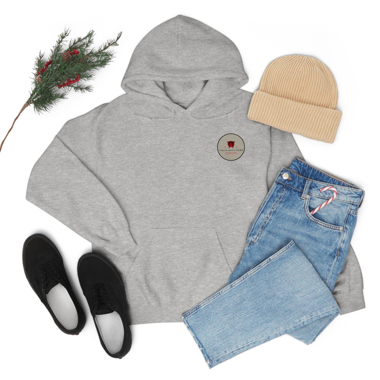 Light gray Wagon Chibi Hoodie laid flat with a beige beanie, light blue jeans holding a candy cane, black sneakers, and a sprig of evergreen with red berries, showcasing casual Japanese car culture streetwear.