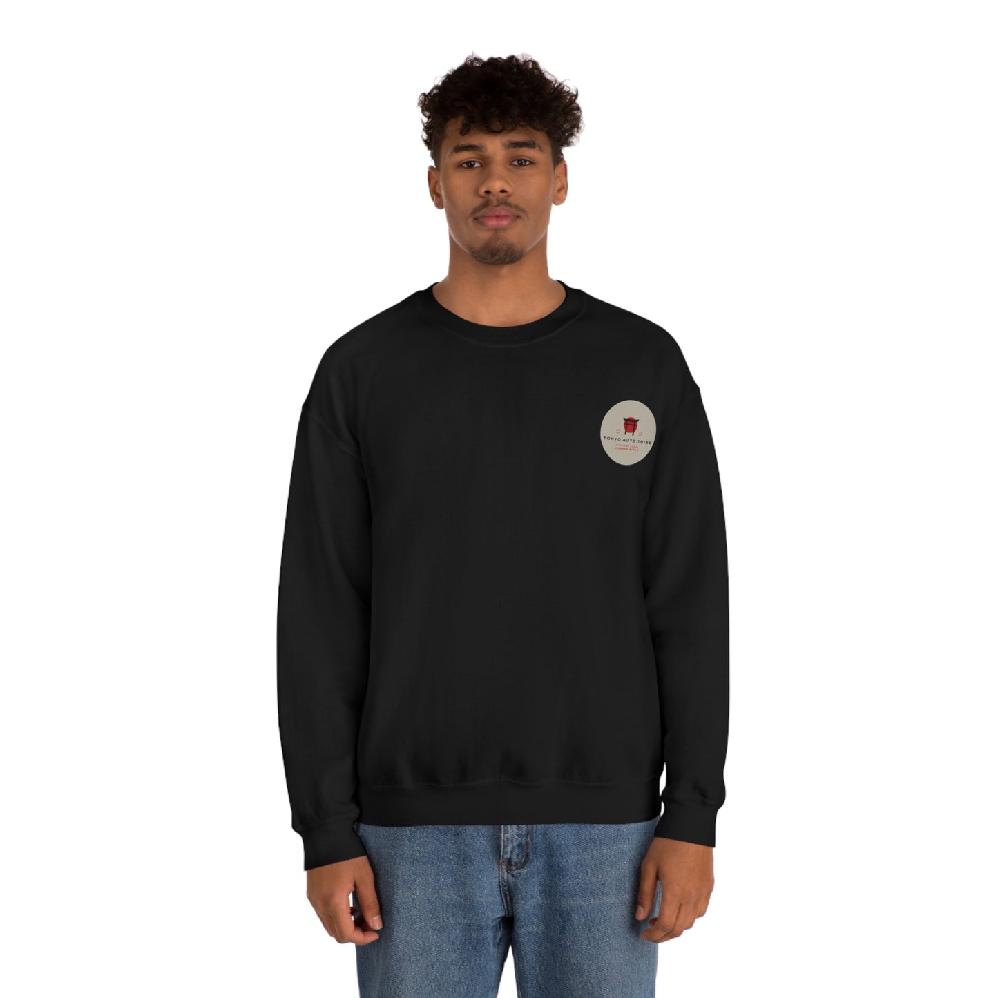 Young man wearing a black Wagon Chibi Sweater with a small red graphic on the chest, styled with blue jeans, embodying Japanese car culture and late-night drive vibes.