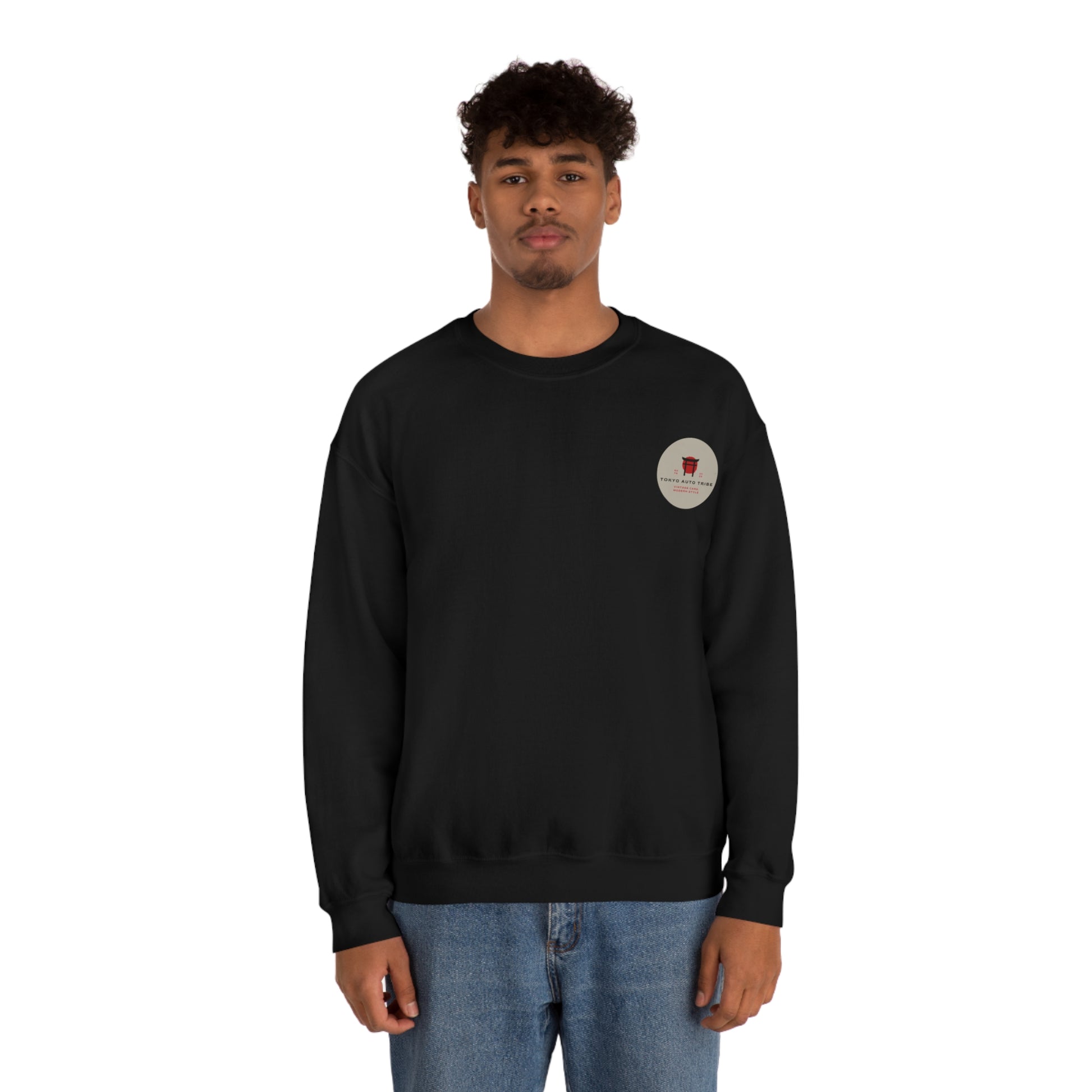 Young man wearing a black Wagon Chibi Sweater with a small red graphic on the chest, styled with blue jeans, embodying Japanese car culture and late-night drive vibes.