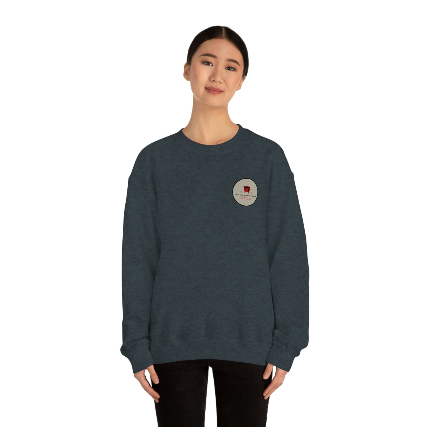 A woman wearing a dark gray crewneck sweatshirt featuring a small round patch with a red car illustration and text on the chest, styled as The Family Wagon Sweater.