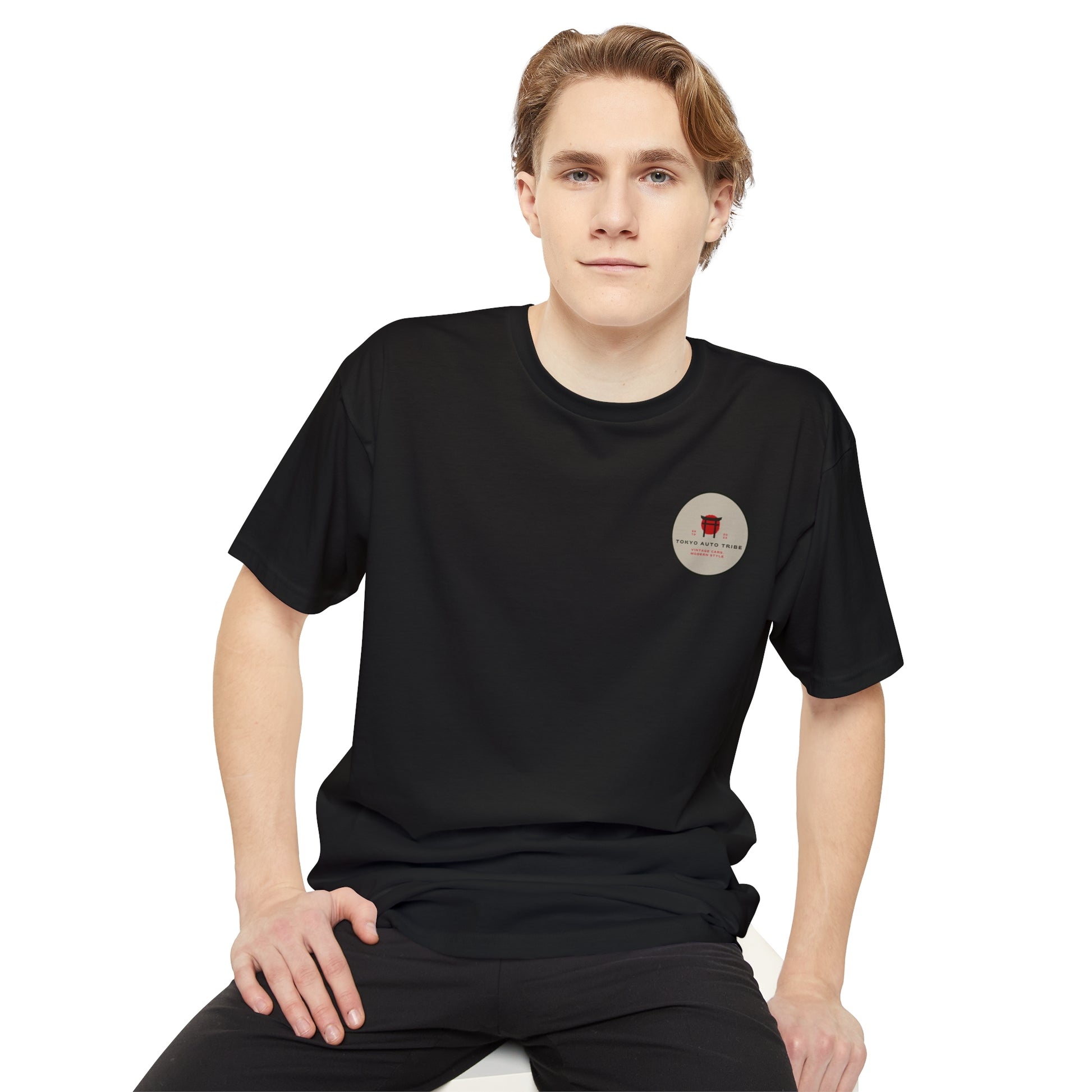Young man wearing a black Unbreakable Spirit oversized T-Shirt featuring a subtle circular graphic, embodying Tokyo Auto Tribe’s late-night Japanese car culture vibe.