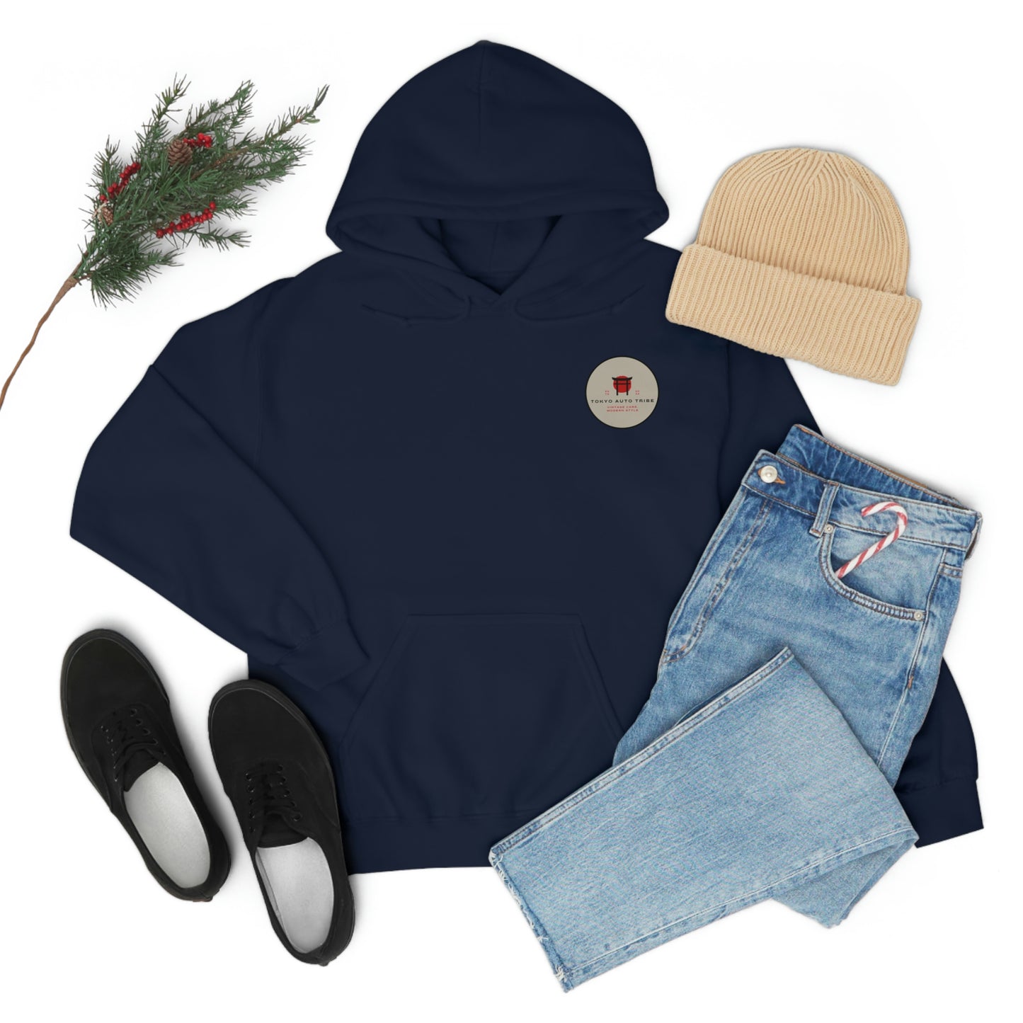 Flat lay of a navy Groovy Grocery Runner Hoodie styled with light blue jeans, black casual shoes, a beige knit beanie, and festive pine branch with red berries, capturing cozy streetwear vibe.