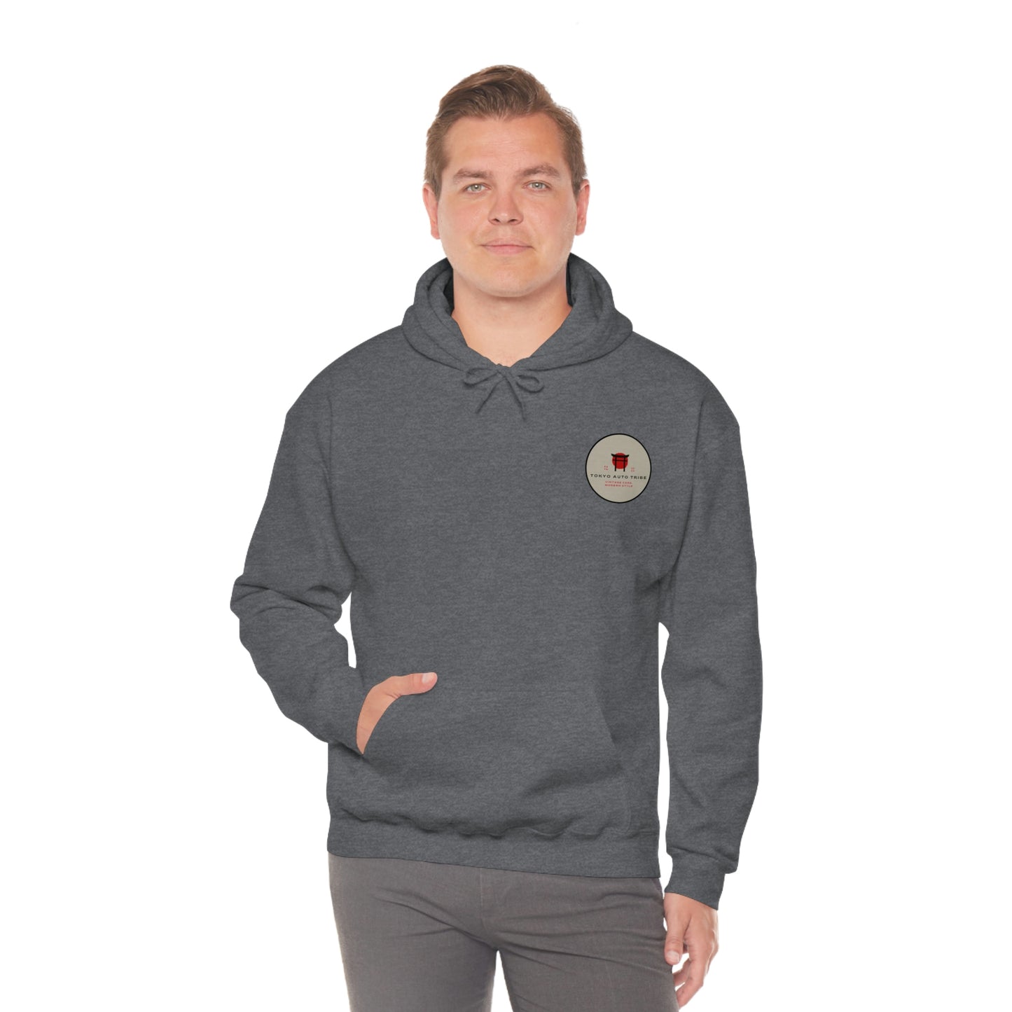 Man wearing a dark gray Groovy Grocery Runner Hoodie with a small circular vintage-style graphic on the chest, designed for fans of Japanese car culture and late-night drives.