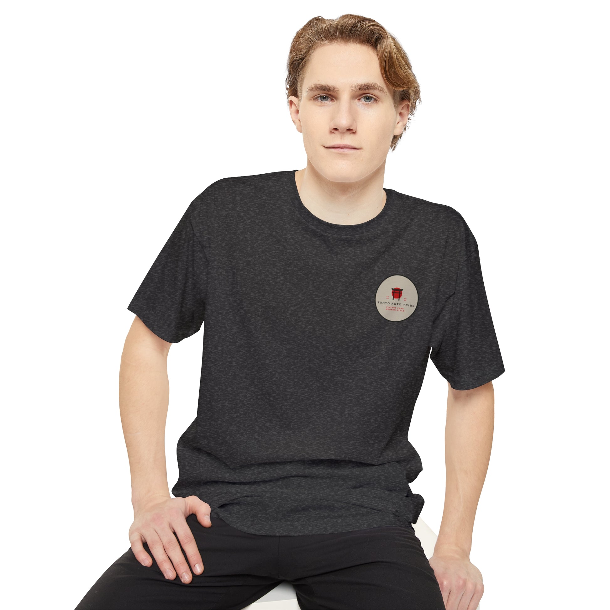 Young man wearing a black Unbreakable Spirit oversized T-Shirt with a small red graphic on the chest, embodying late-night Japanese car culture and tuner lifestyle.