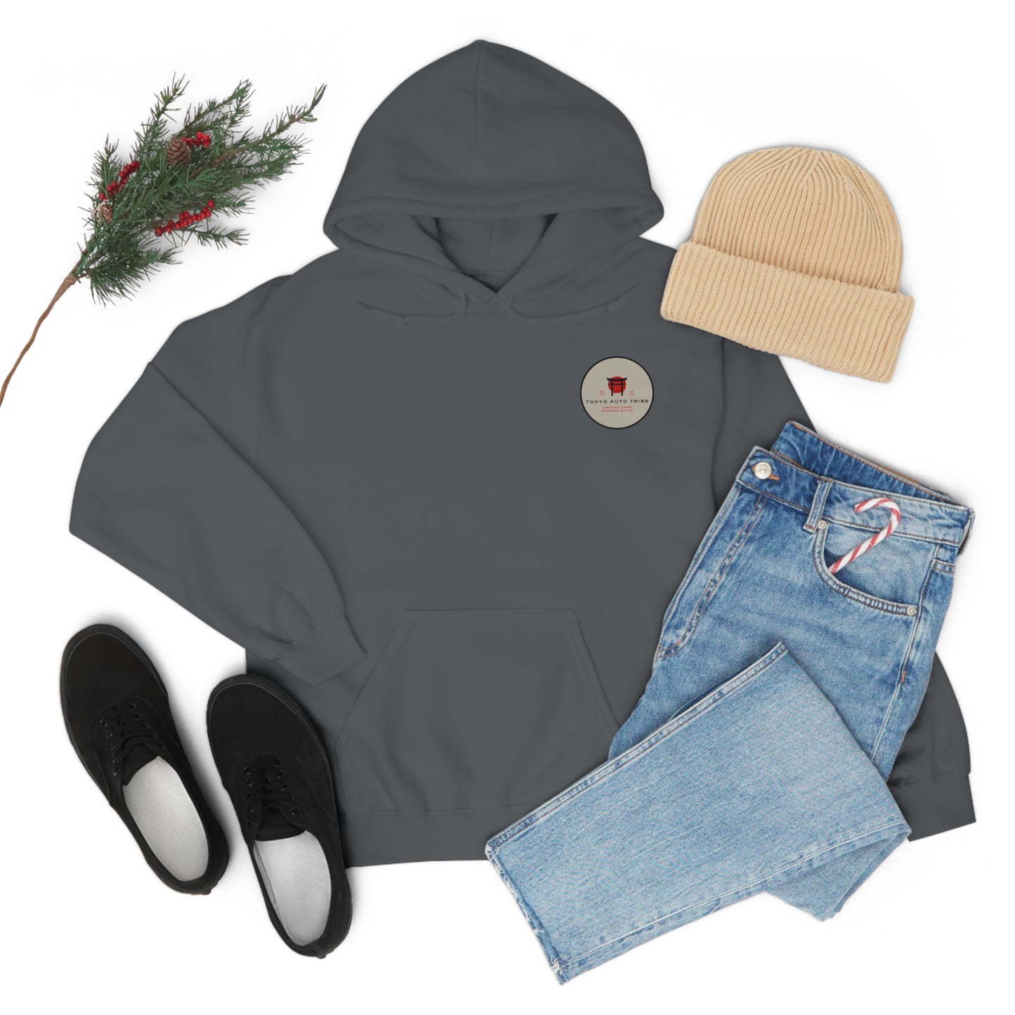 Dark gray Wagon Chibi Hoodie laid flat with light blue jeans featuring a candy cane in the pocket, beige knit beanie, black slip-on shoes, and a pine branch with red berries, evoking Japanese car culture and late-night drives.