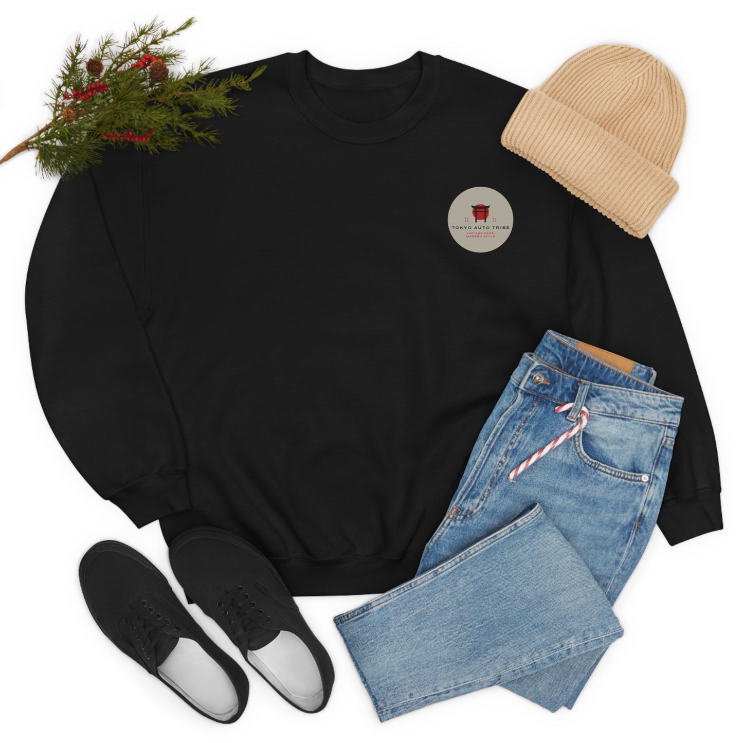 Black Wagon Chibi Sweater with a small circular graphic, paired with light blue jeans, black slip-on shoes, and a beige knit beanie, styled with greenery accents.