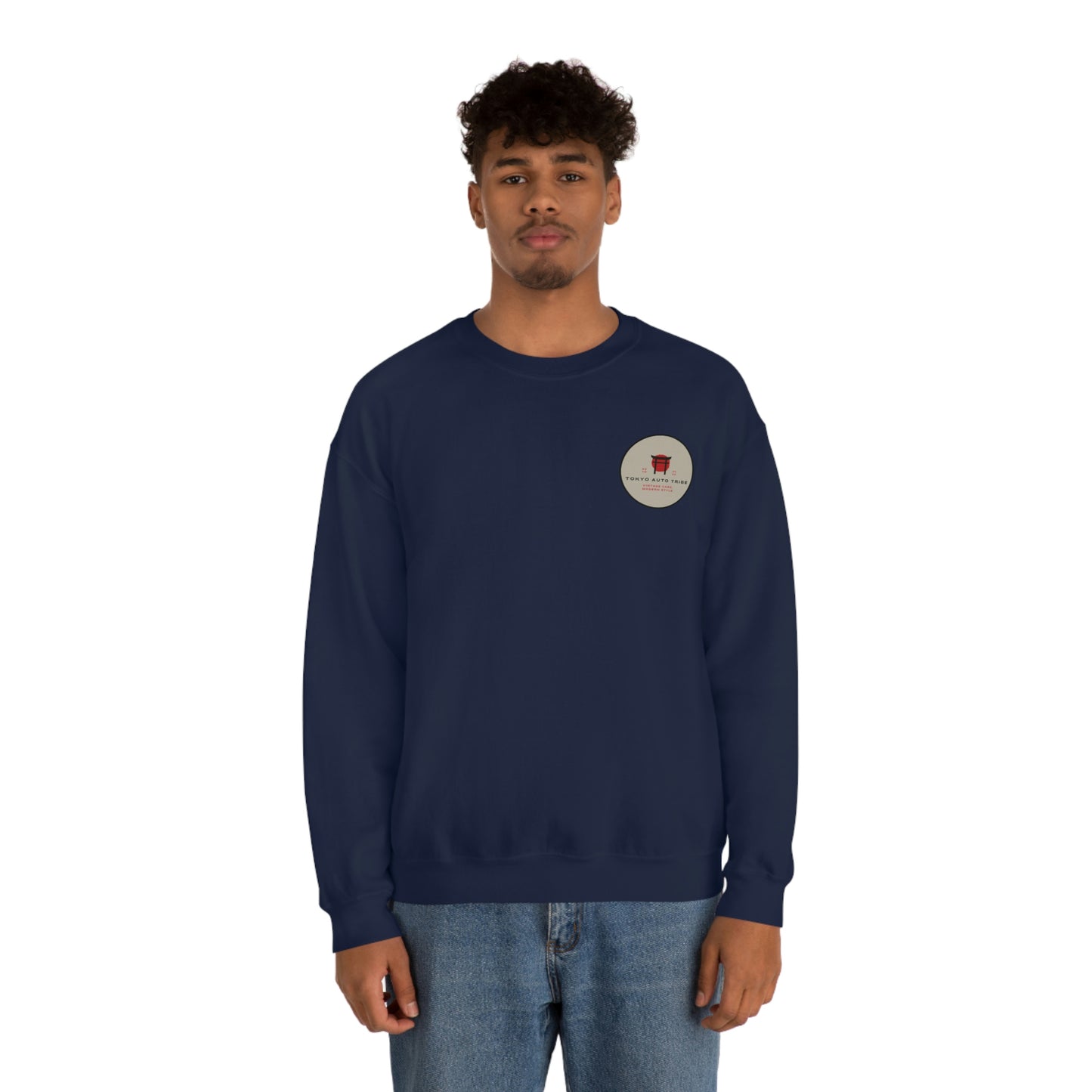A man wearing a navy blue crewneck sweatshirt with a small circular graphic on the chest, featuring The Family Wagon Sweater inspired by Japanese car culture and late-night drives.