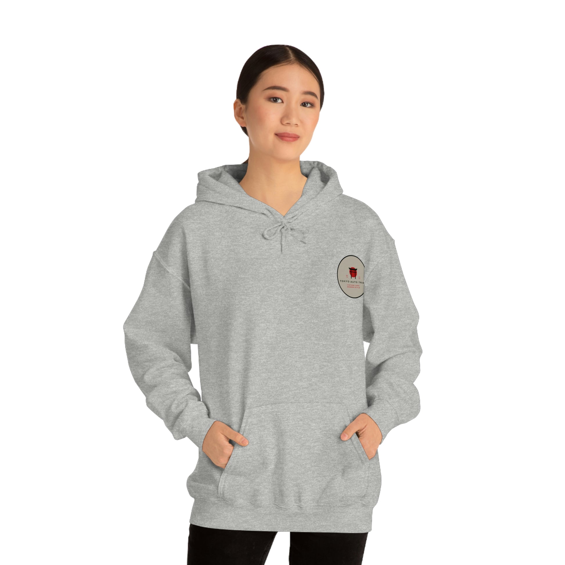 Woman wearing a light gray Groovy Grocery Runner Hoodie with a small round graphic on the chest, styled for fans of Japanese car culture and streetwear.