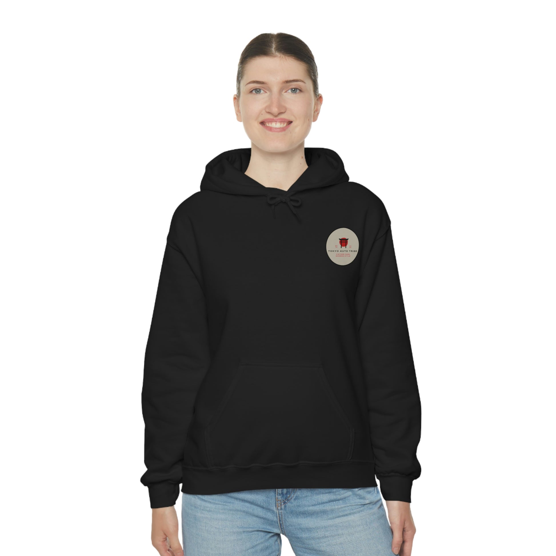 A smiling woman wearing a black Godzilla's Fury Hoodie with a small circular graphic on the chest, paired with light blue jeans against a white background.