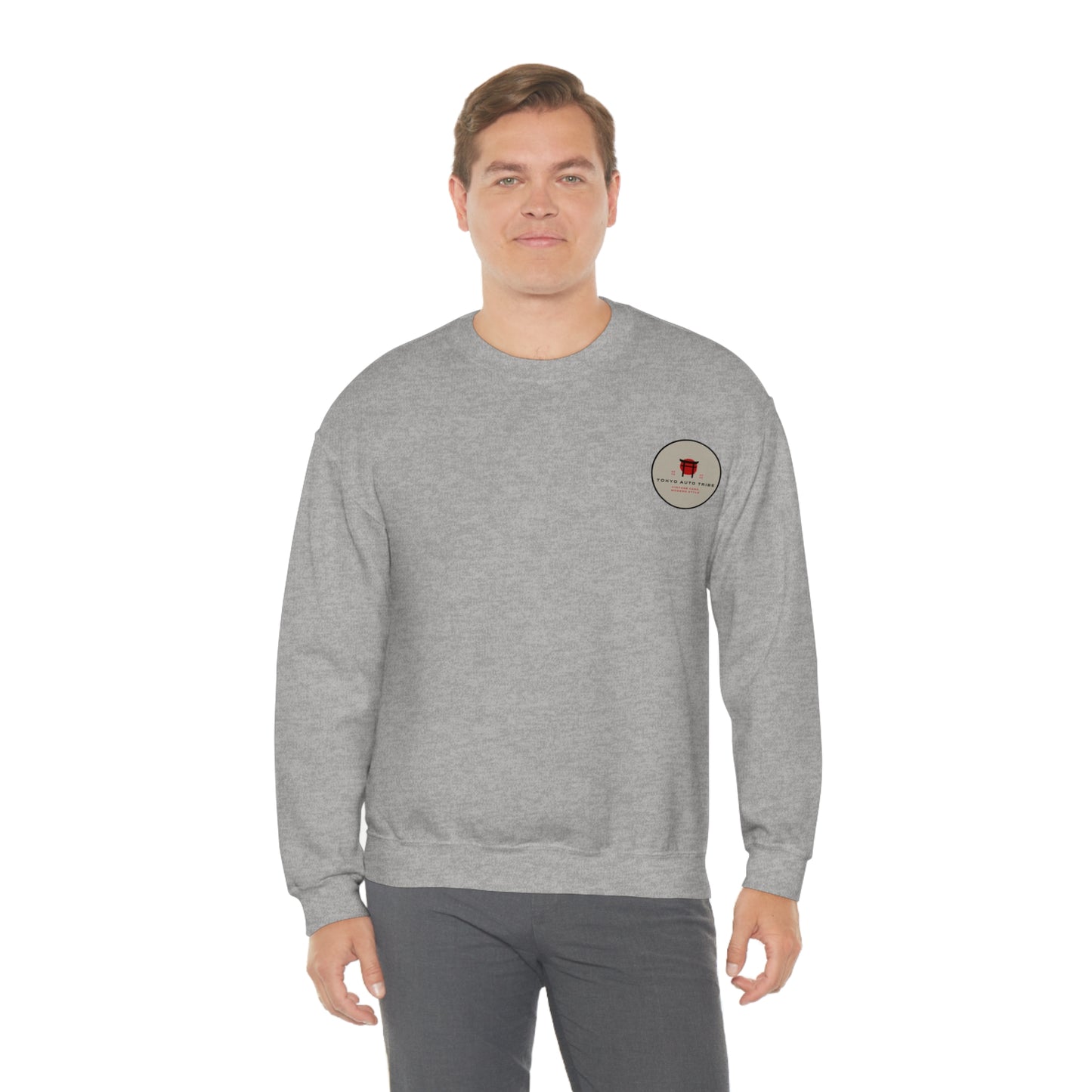 A man wearing a gray Wagon Chibi Sweater featuring a small red graphic on the chest, representing Japanese car culture and late-night drift scenes in a casual streetwear style.