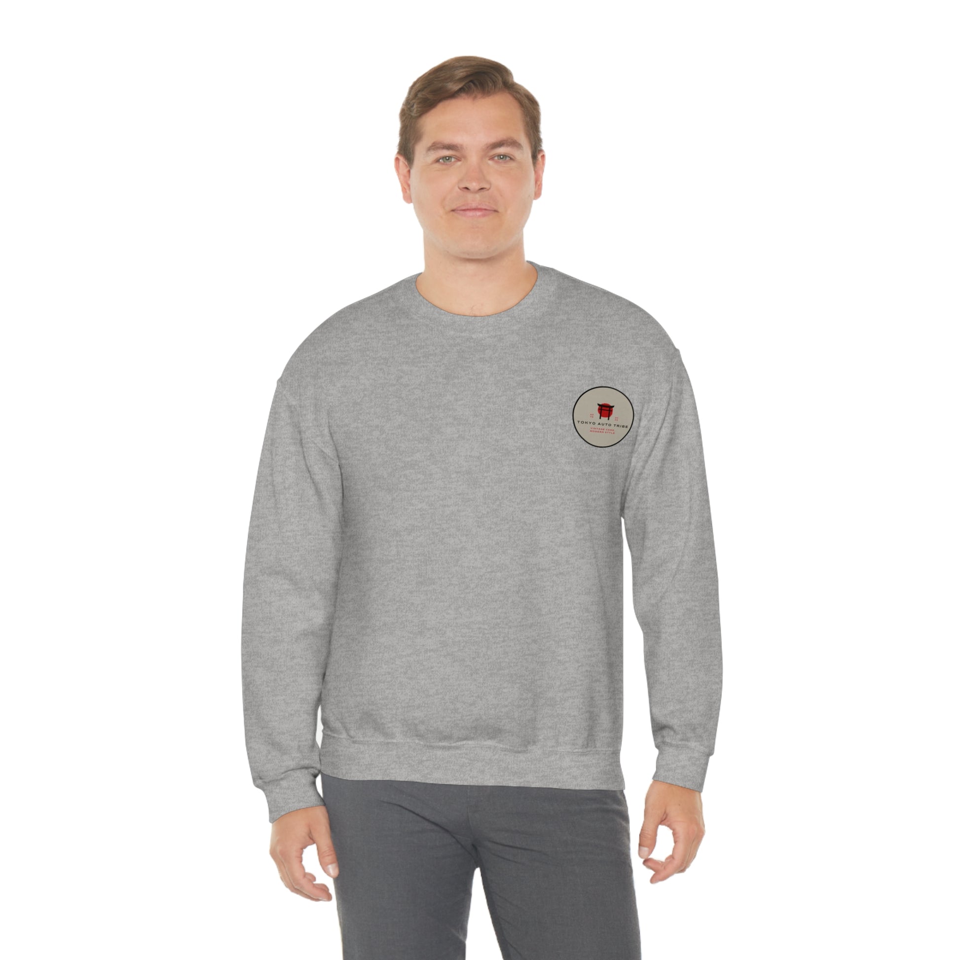 A man wearing a gray Wagon Chibi Sweater featuring a small red graphic on the chest, representing Japanese car culture and late-night drift scenes in a casual streetwear style.