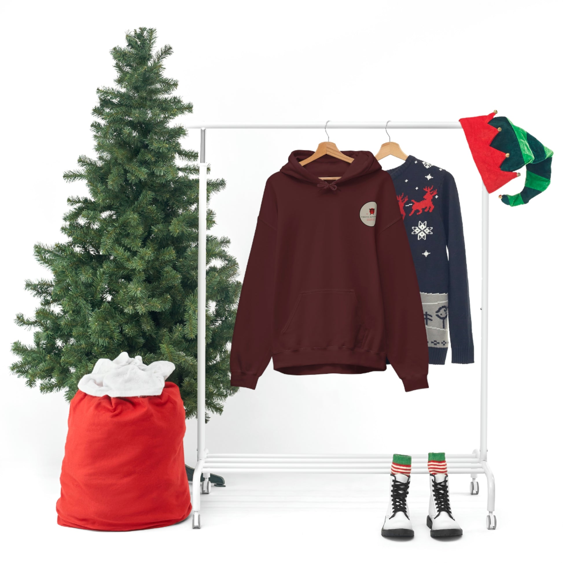 Groovy Grocery Runner Hoodie in deep maroon hanging on a rack next to a festive sweater, with a decorated Christmas tree, red sack, elf hats, and striped boots creating a holiday-themed display.
