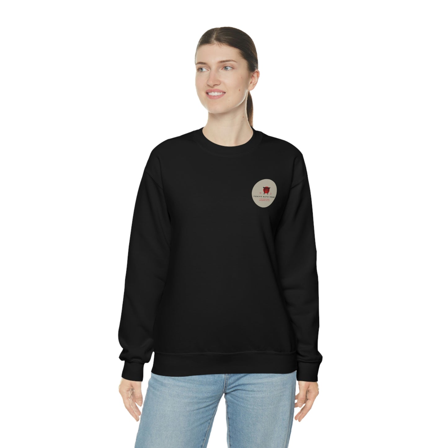 Woman wearing a black sweatshirt with a small circular graphic on the chest, styled casually with light blue jeans, featuring The Family Wagon Sweater inspired by Japanese car culture.