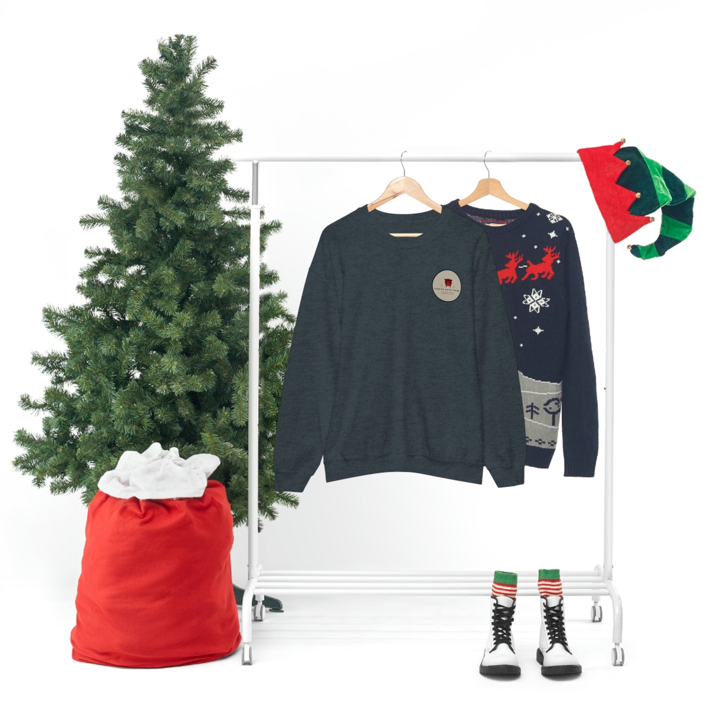 Two sweaters including The Family Wagon Sweater with a dark tone hanging on a rack beside a Christmas tree and holiday decorations evoking Japanese tuner car culture and late-night drive vibes.