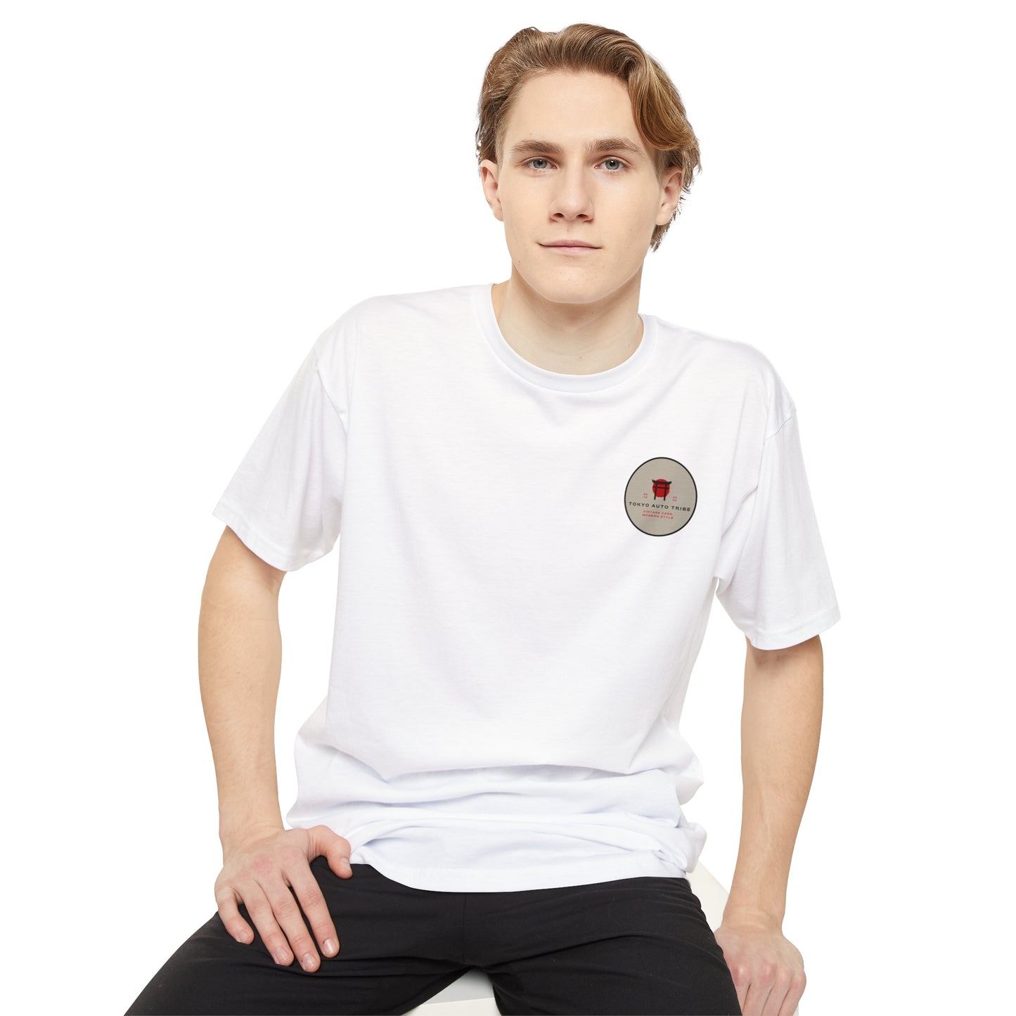 Young man wearing a white Unbreakable Spirit oversized T-Shirt featuring a small red graphic on the chest, styled casually to reflect Japanese car culture and streetwear.