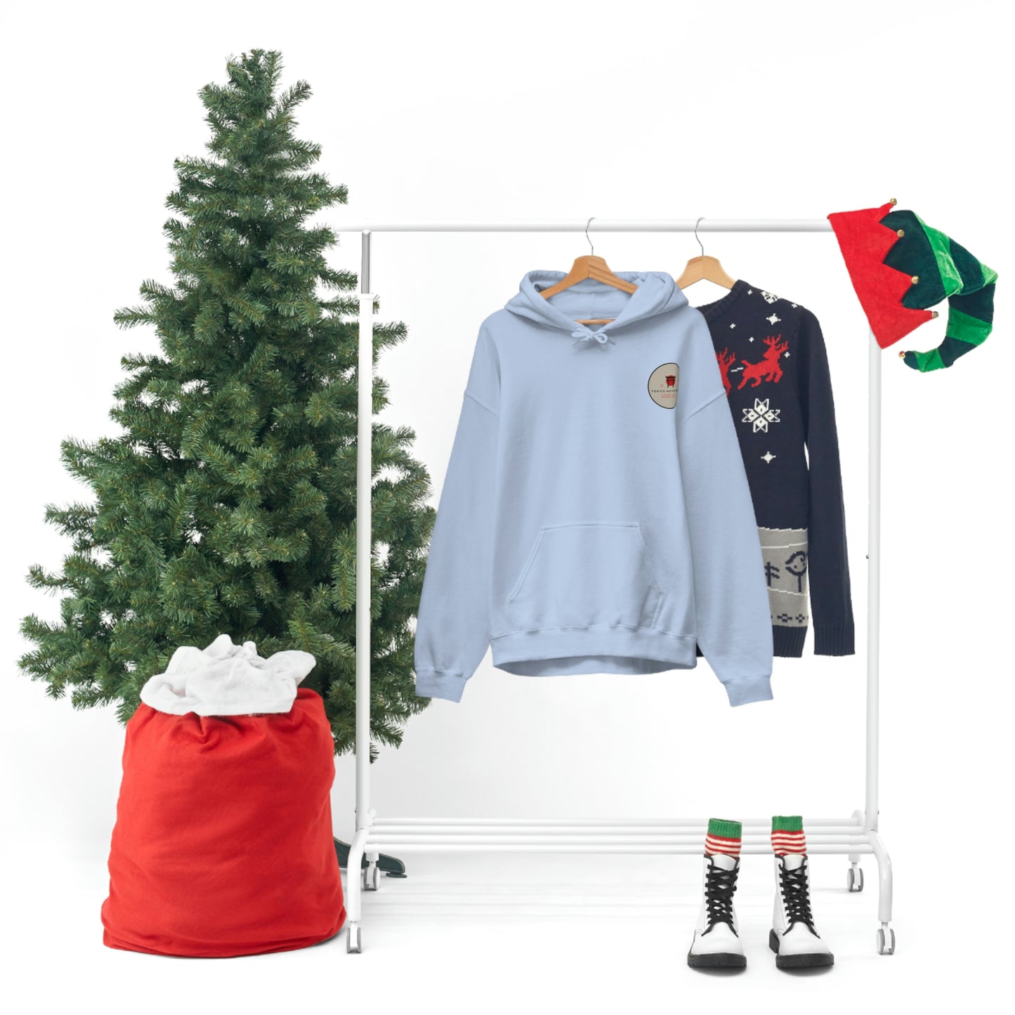 Light blue Groovy Grocery Runner Hoodie displayed with festive holiday decor, a Christmas tree, and a sporty black sweater featuring winter-themed graphics.