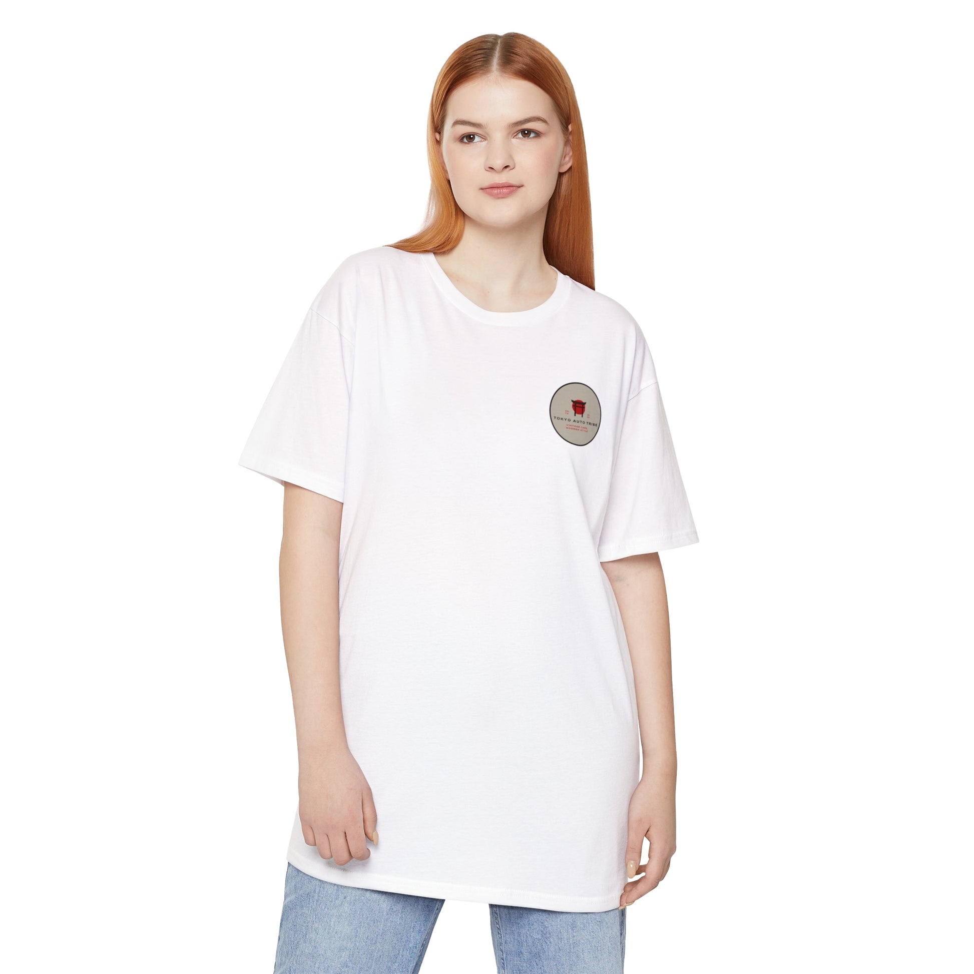 Woman wearing a white Unbreakable Spirit oversized T-Shirt with a small graphic on the chest, styled casually with light blue jeans, reflecting a relaxed automotive streetwear vibe.