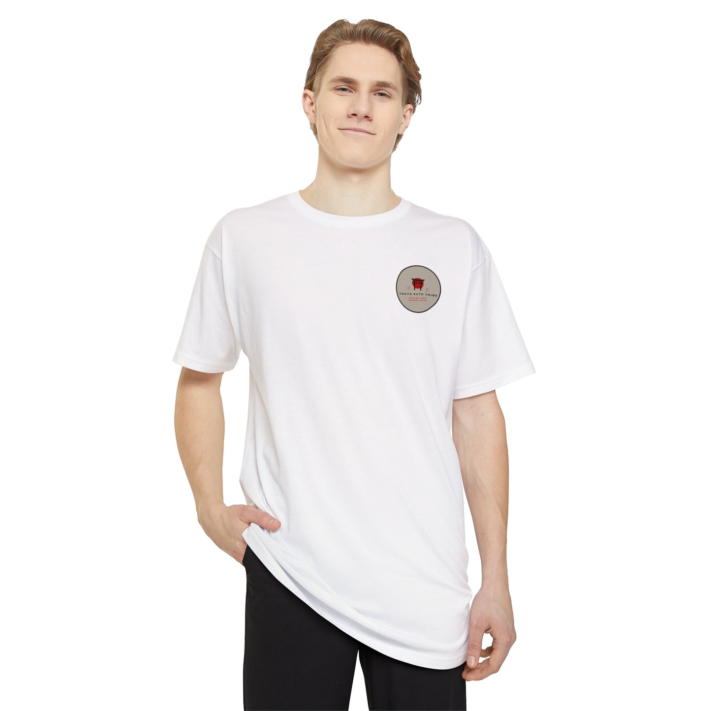 A young man wearing a white Unbreakable Spirit oversized T-Shirt featuring a small round graphic on the chest, styled for fans of Japanese car culture and automotive streetwear.