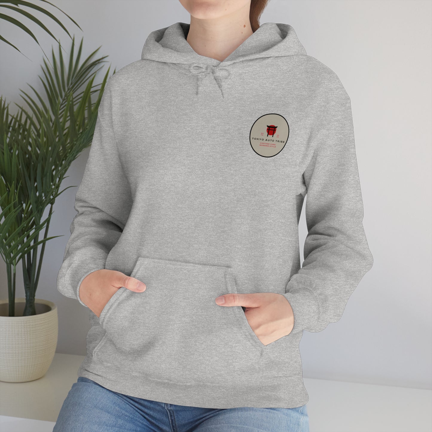 Person wearing a light gray Wagon Chibi Hoodie with a small red and black circular graphic on the chest, styled for fans of Japanese car culture and late-night drift drives.