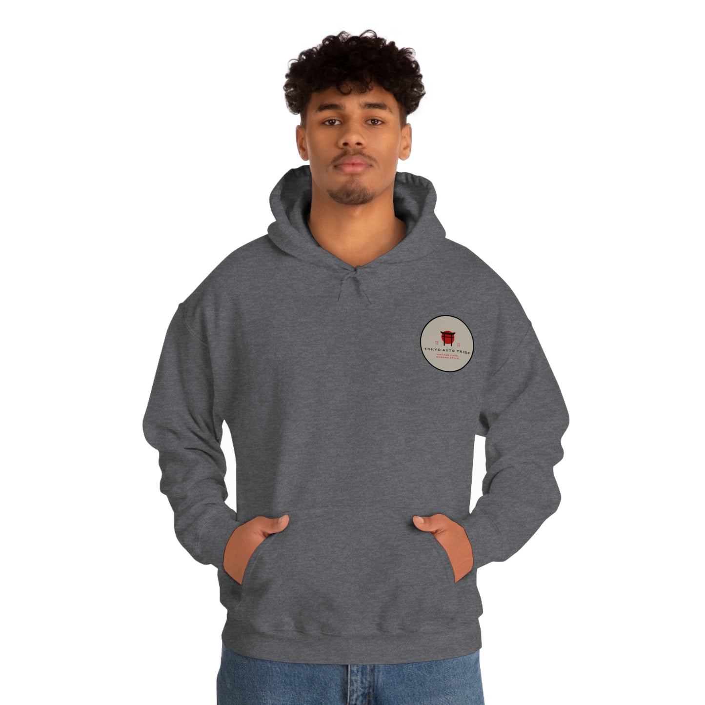 Man wearing a dark gray Wagon Chibi Hoodie with front pocket and hood, featuring a small round graphic logo on the chest, embodying Japanese car culture and tuner lifestyle.
