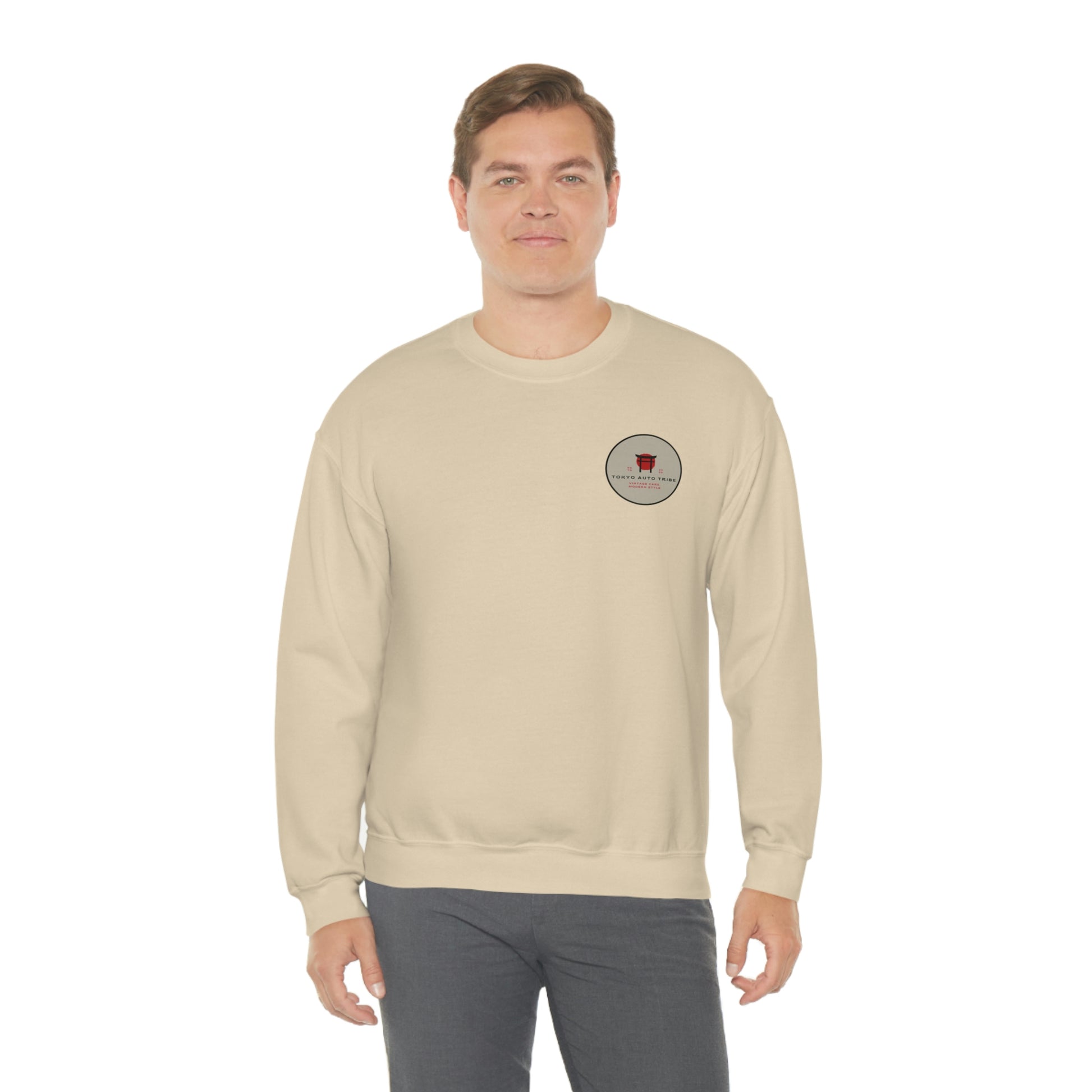 Man wearing The Family Wagon Sweater, a beige crewneck sweatshirt featuring a small round vintage Japanese car culture graphic on the chest, styled for automotive streetwear fans.