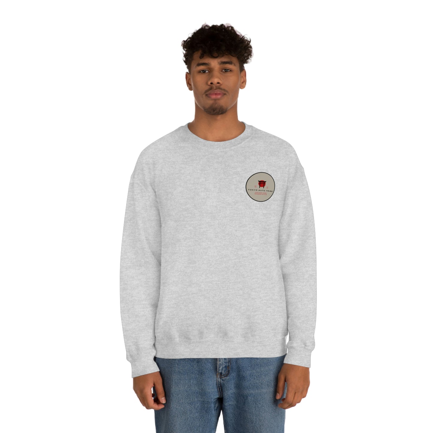 Man wearing a light gray crewneck sweatshirt with a small vintage-style graphic on the chest, showcasing The Family Wagon Sweater designed for fans of Japanese car culture and late-night drives.